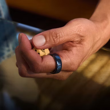 Close up of a person's hand with a Midnight Oura Ring 4 Ceramic on their finger